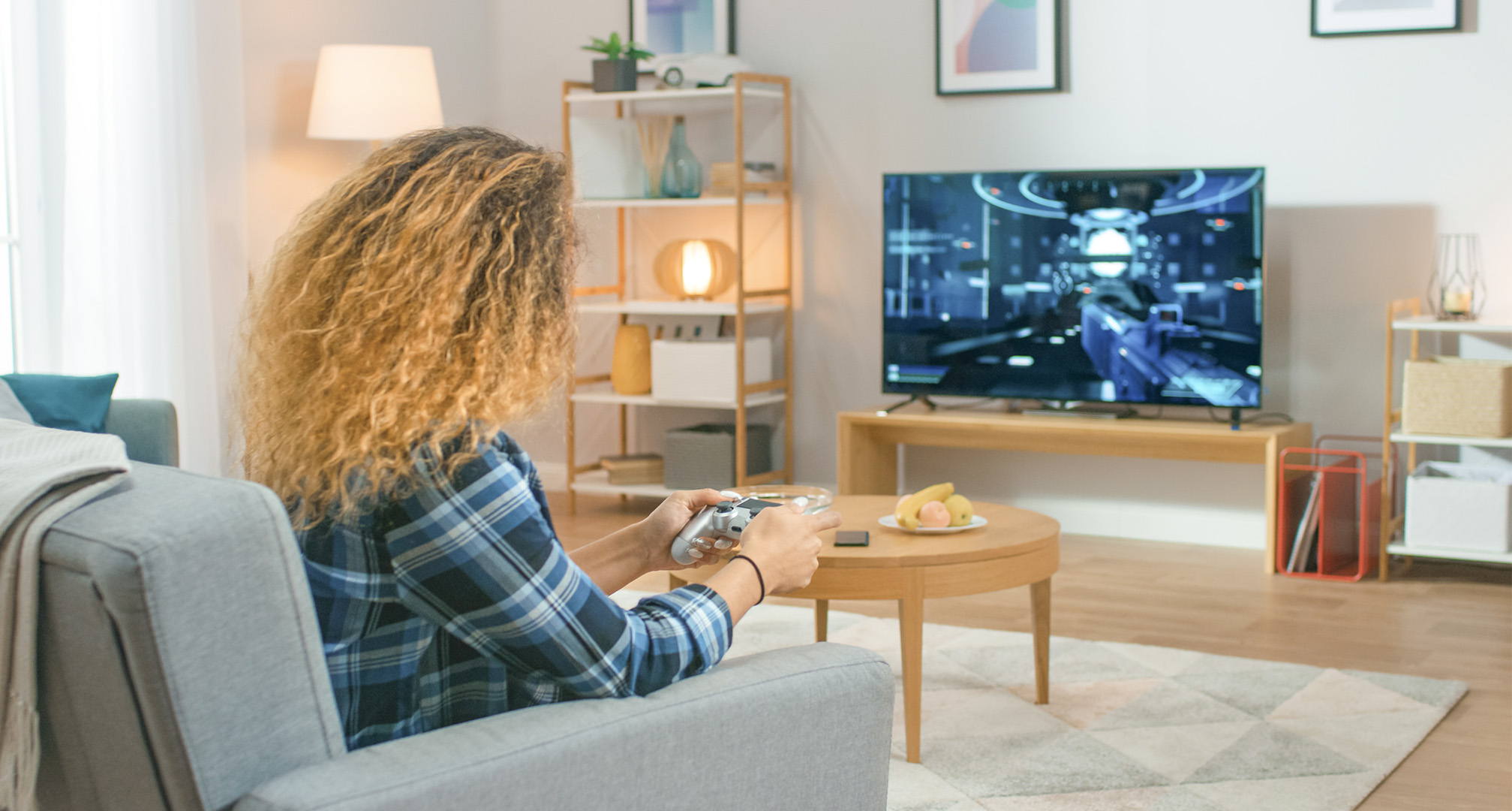 personne aux cheveux longs et bouclés dans un salon jouant à des jeux vidéo sur une télévision
