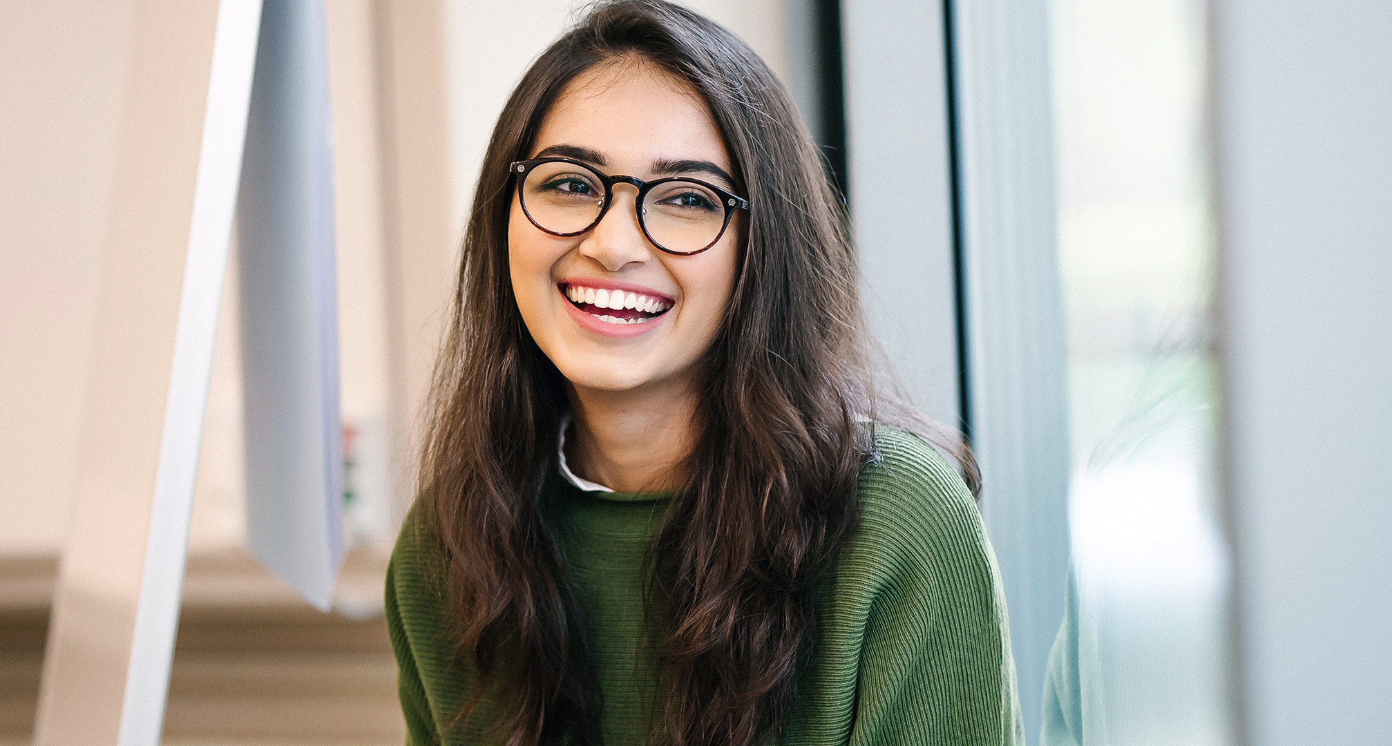 photo d'une personne souriante aux cheveux longs portant des lunettes noires