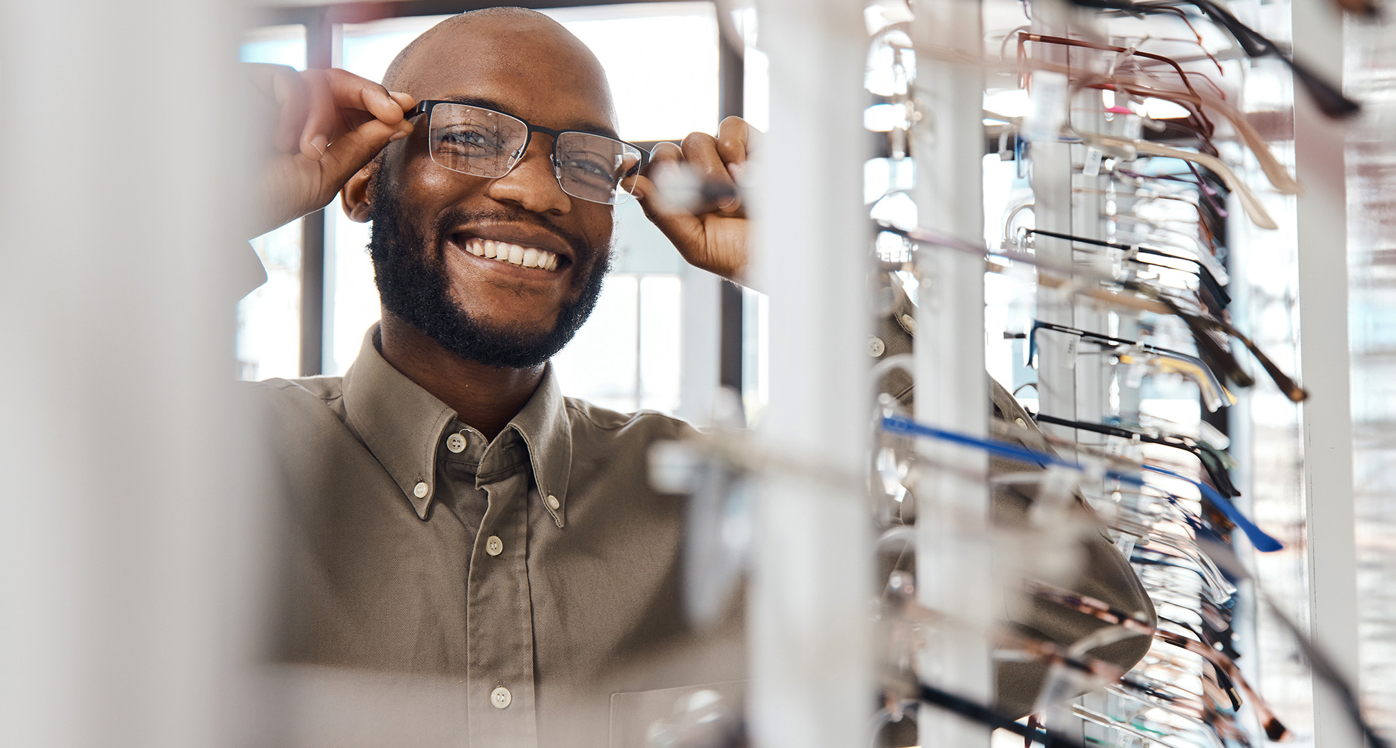 photo d'une personne souriante essayant des lunettes chez un opticien